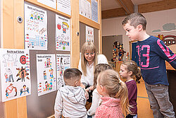 Kinder und Kita-Leiterin Manuela Pascarella sprechen über Kinderrechte, die an einer Wand dargestellt sind. Foto: Prot. Kita-Verbund LU/Wagner 