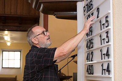 Karl-Heinz Meister richtet die Liedtafel für den Gottesdienst. Foto: lk/Wagner